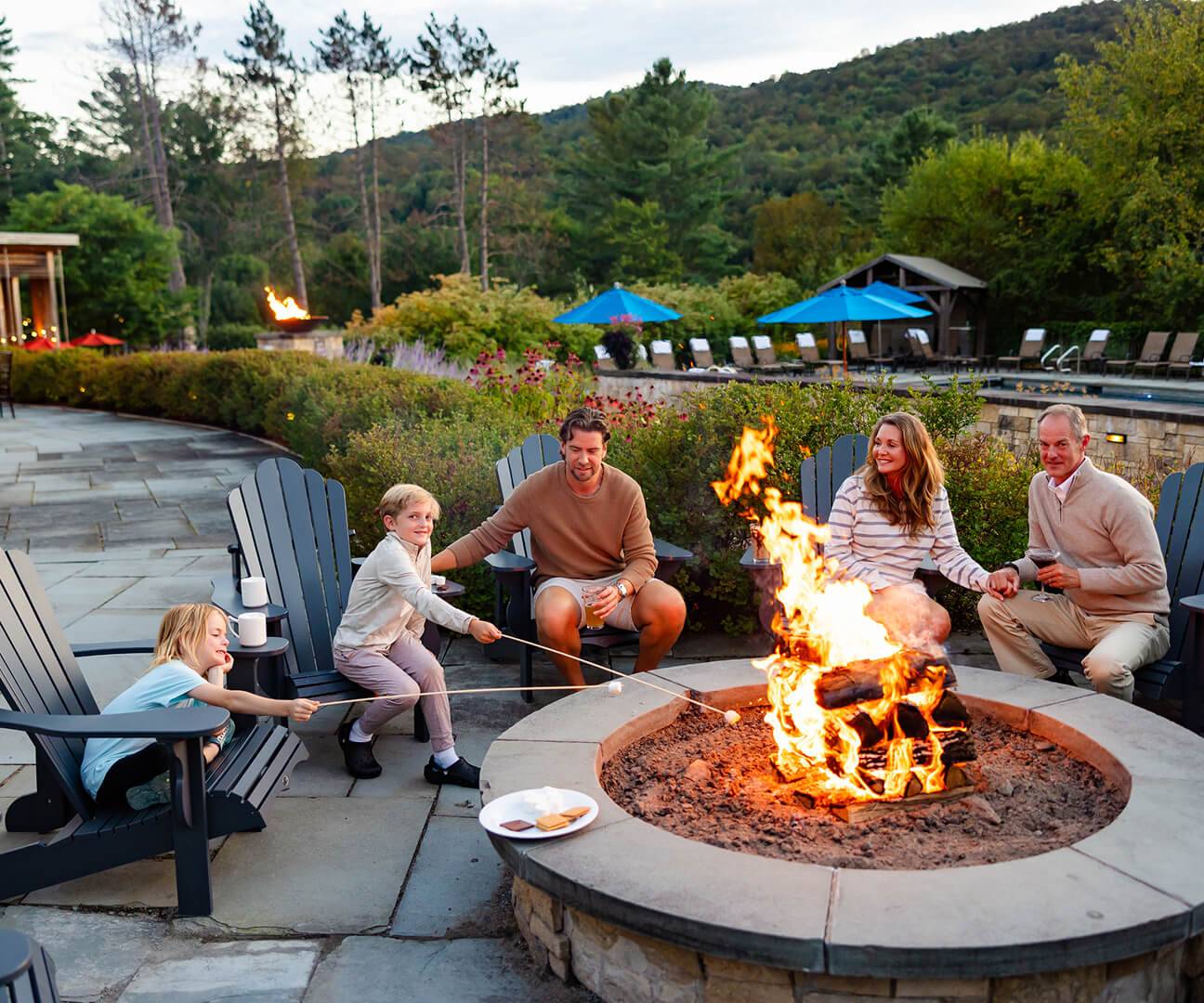 Hotel guests gathered around the fire pit roasting marshmallows